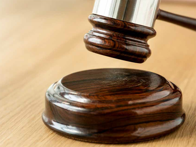 Ein Richterhammer über einem runden Holzblock auf einem Tisch.